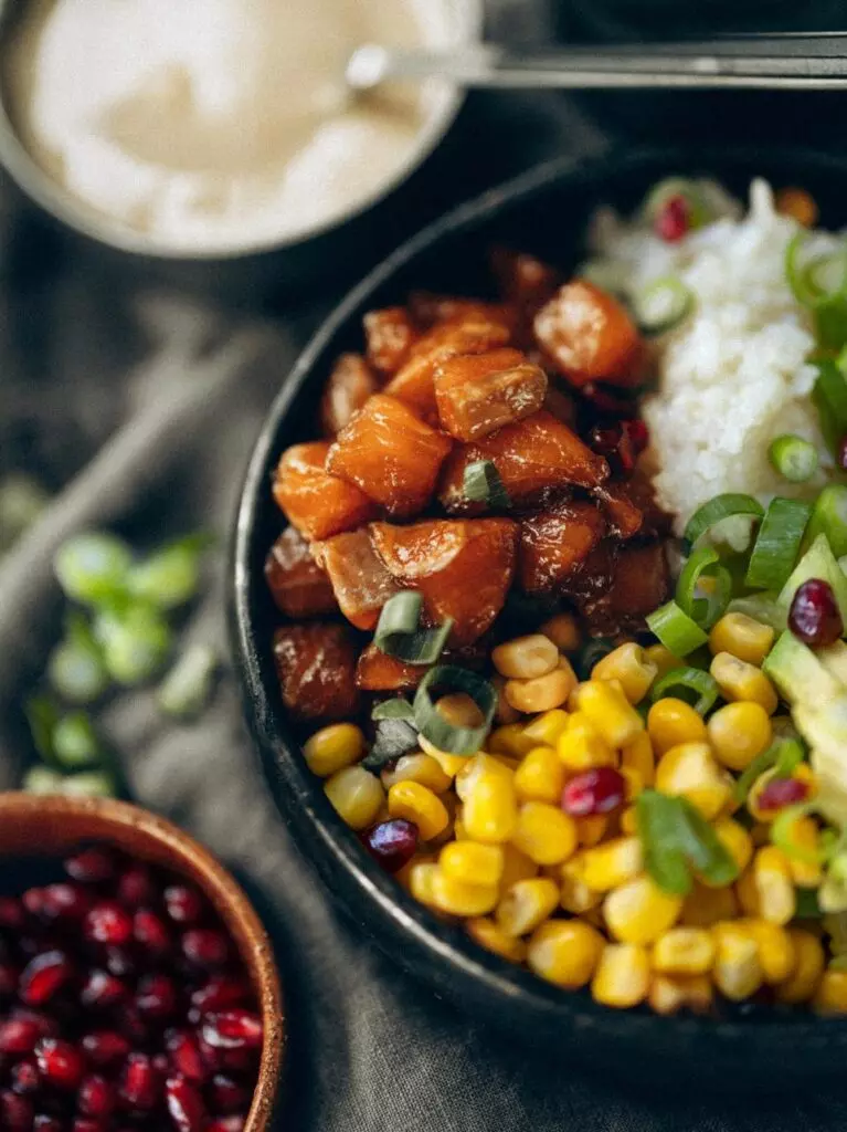 Pokébowl met zalm, avocado, granaatappelpitjes en sesamsaus