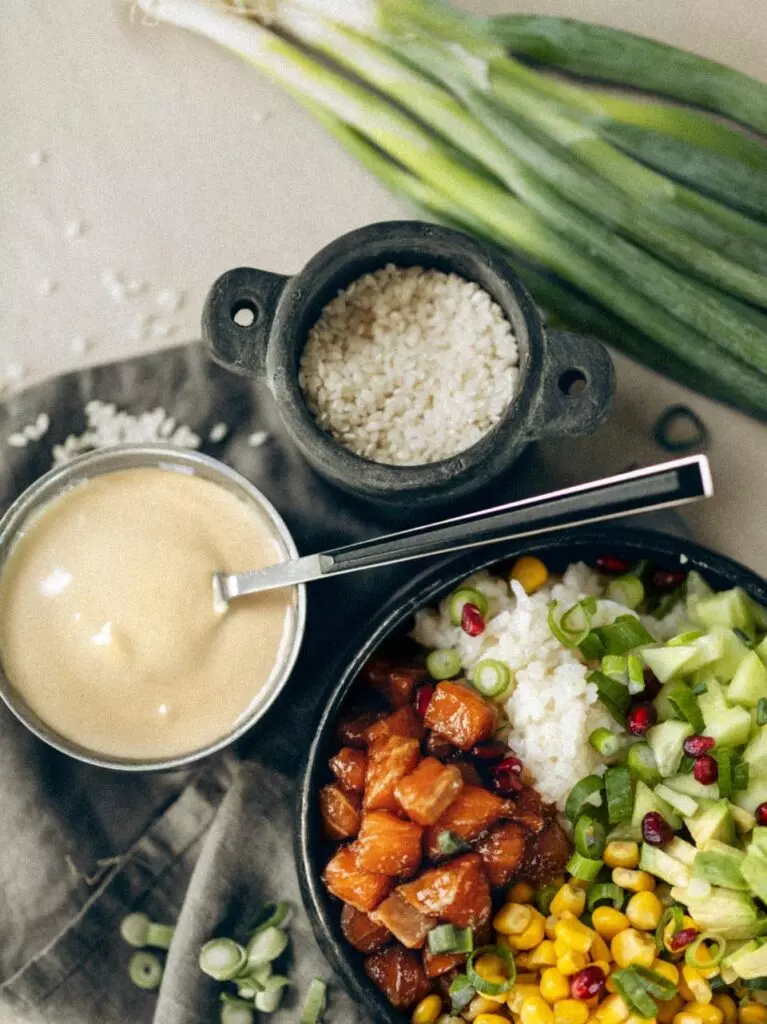 Pokébowl met zalm, avocado, granaatappelpitjes en sesamsaus