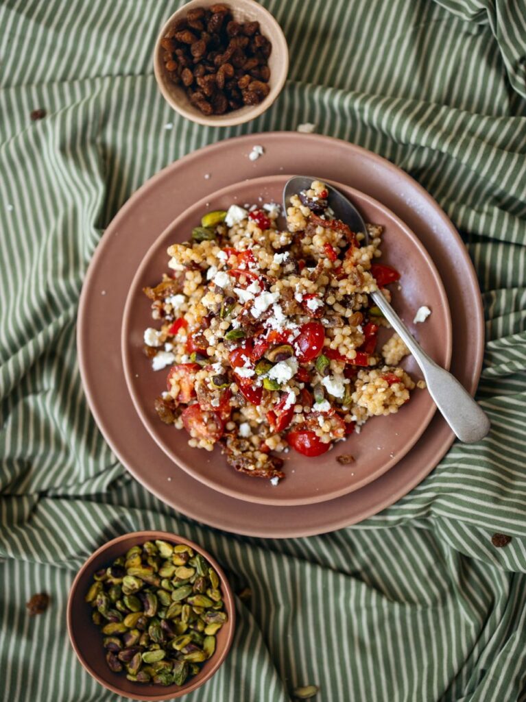 Parelcouscous salade met paprika, feta, zongedroogde tomaat en geroosterde pistache